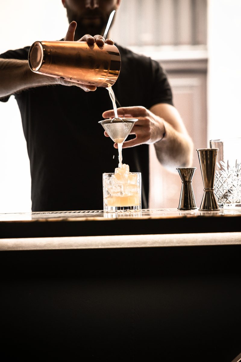 Cocktail versé au shaker derrière le comptoir de Liquide
